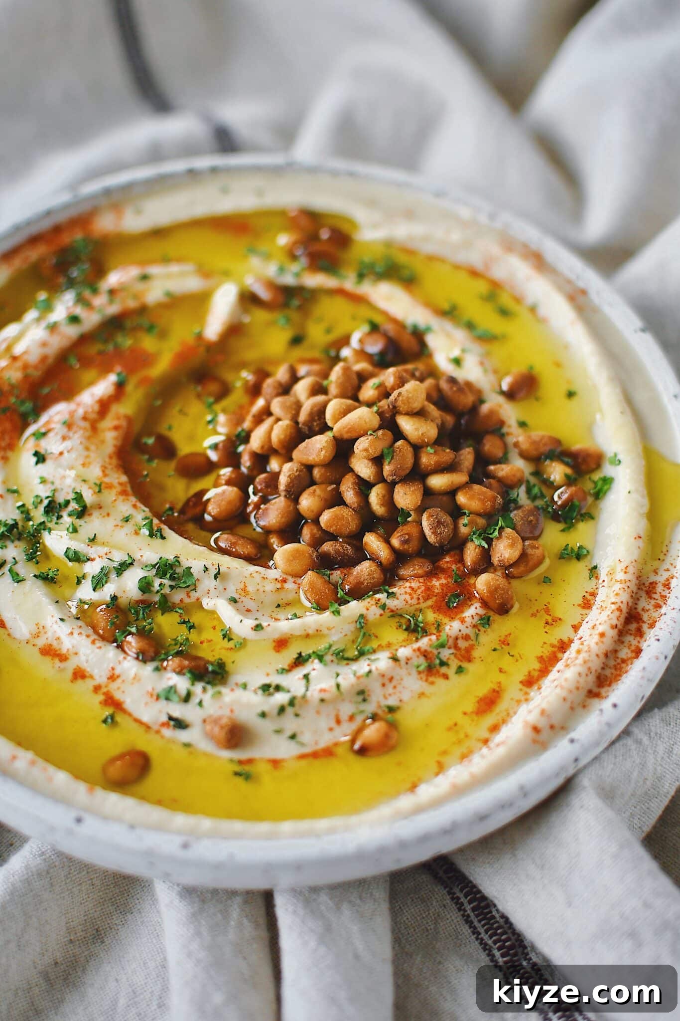 Creamy Homemade Hummus: Simple Recipe with Tahini & Lemon 2 Homemade Hummus, topped with olive oil, paprika, toasted pine nuts, and parsley, ready to eat.