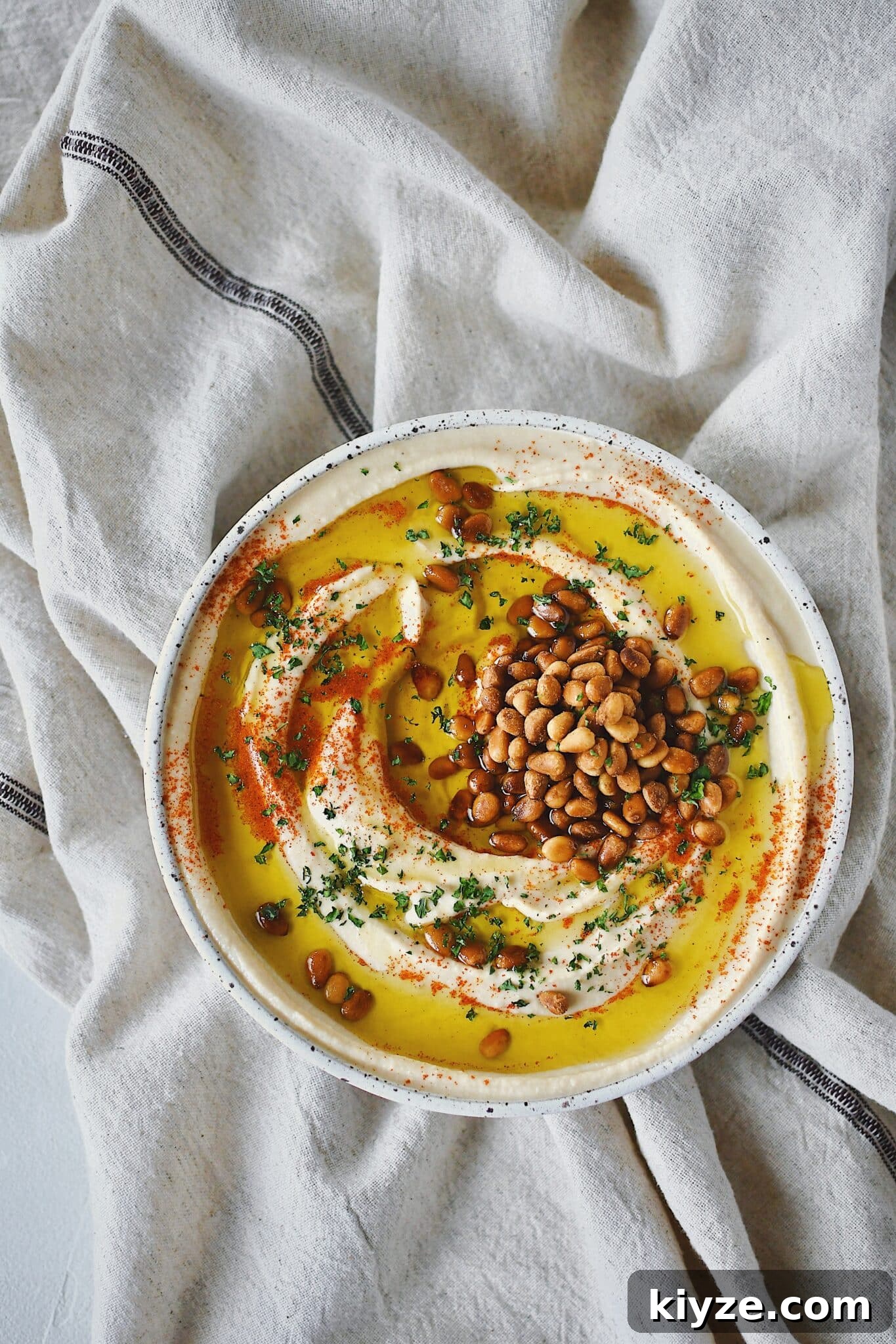 Creamy Homemade Hummus: Simple Recipe with Tahini & Lemon 13 Homemade Hummus, topped with olive oil, paprika, toasted pine nuts, and parsley, ready to eat.