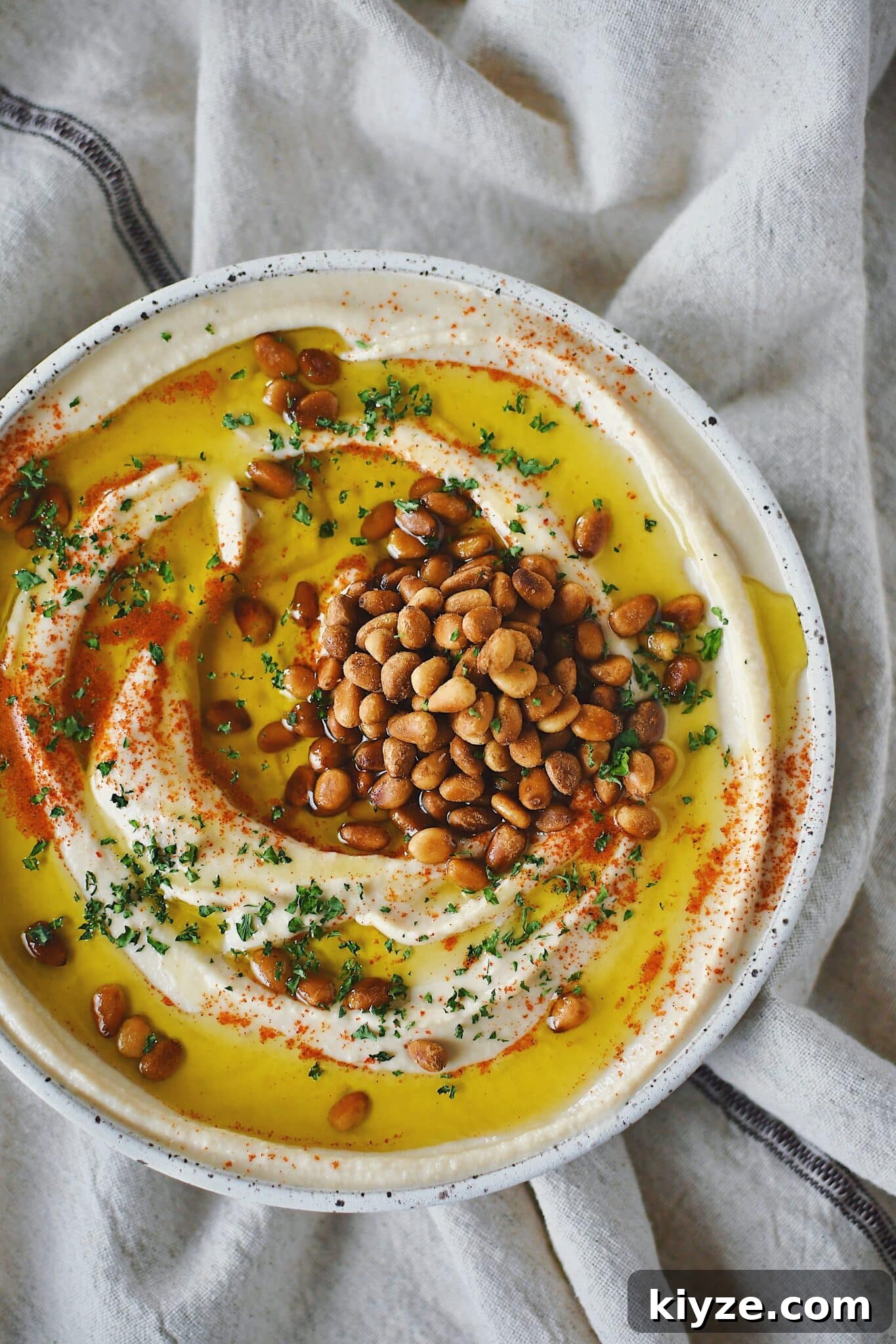 Creamy Homemade Hummus: Simple Recipe with Tahini & Lemon 9 Homemade Hummus, topped with olive oil, paprika, toasted pine nuts, and parsley, ready to eat.