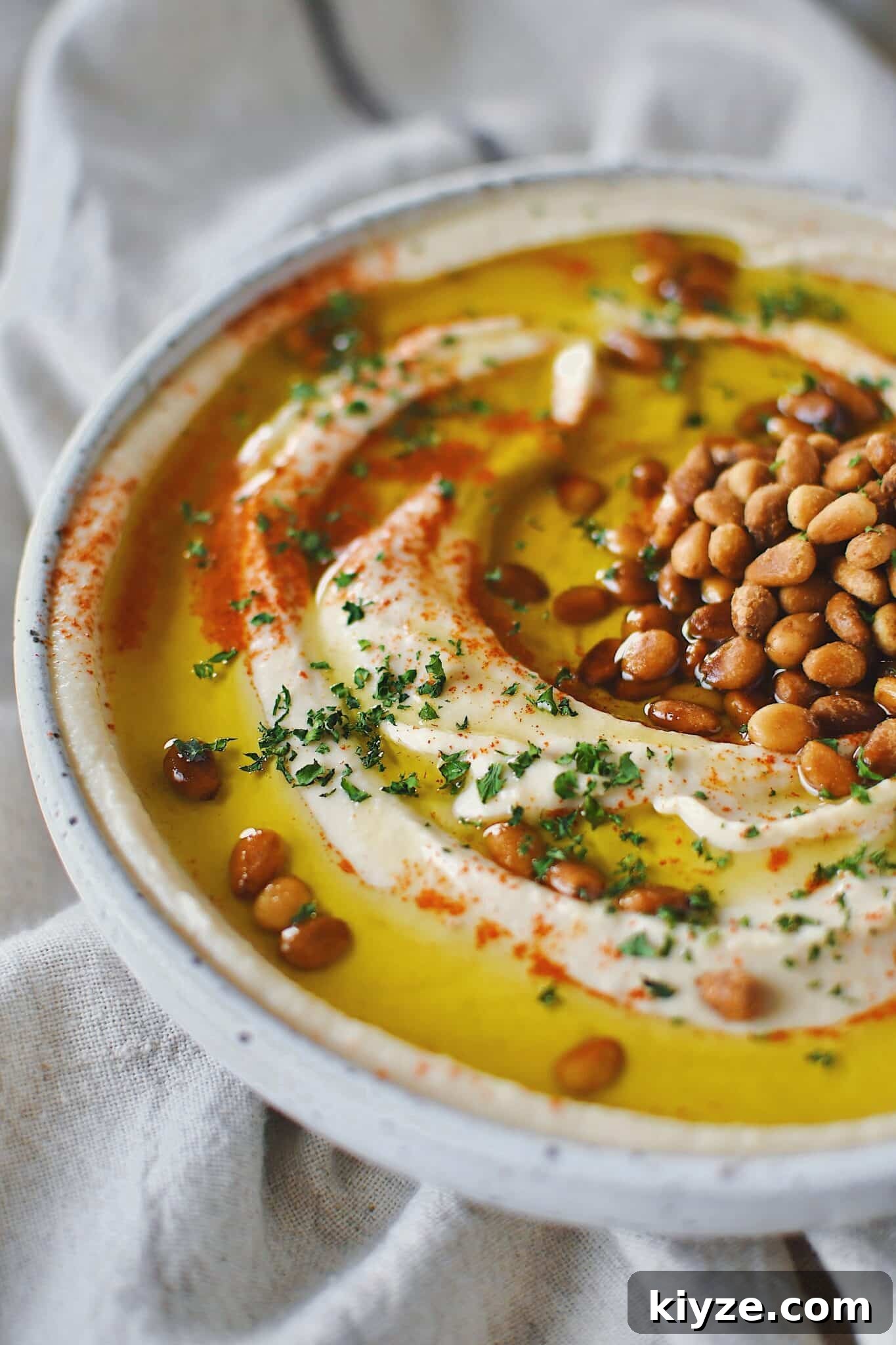 Creamy Homemade Hummus: Simple Recipe with Tahini & Lemon 10 Homemade Hummus, topped with olive oil, paprika, toasted pine nuts, and parsley, ready to eat.
