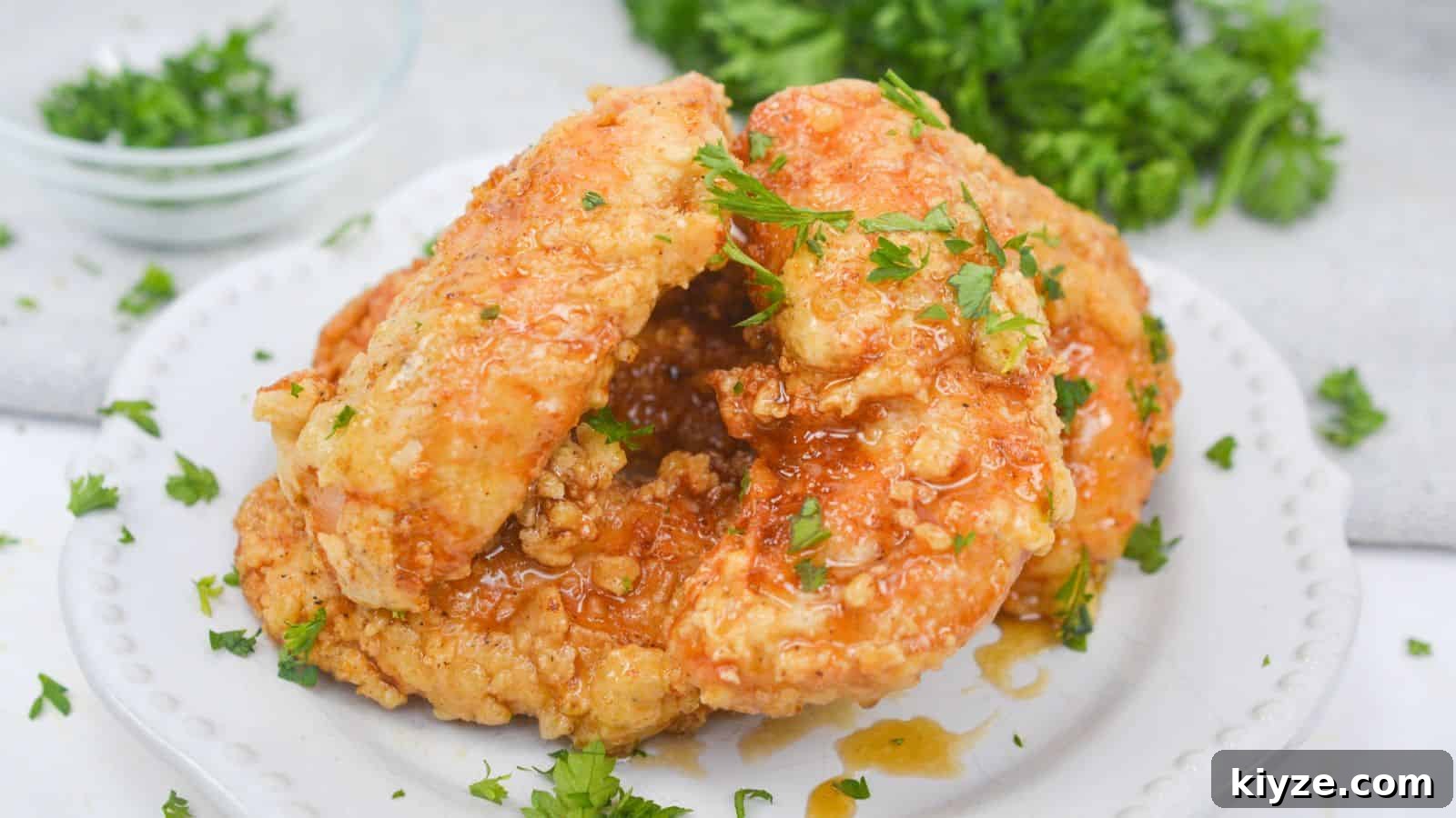 Serving of honey butter chicken garnished with parsley on plate.