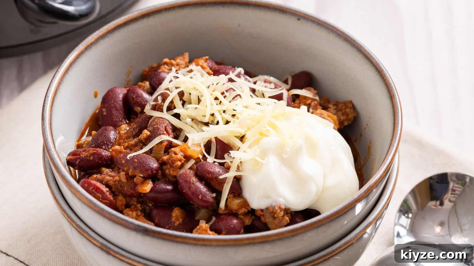 25 Comforting Main Dishes That Make You Forget the Grill 17 Crock Pot Chili served in two white bowls with spoon.