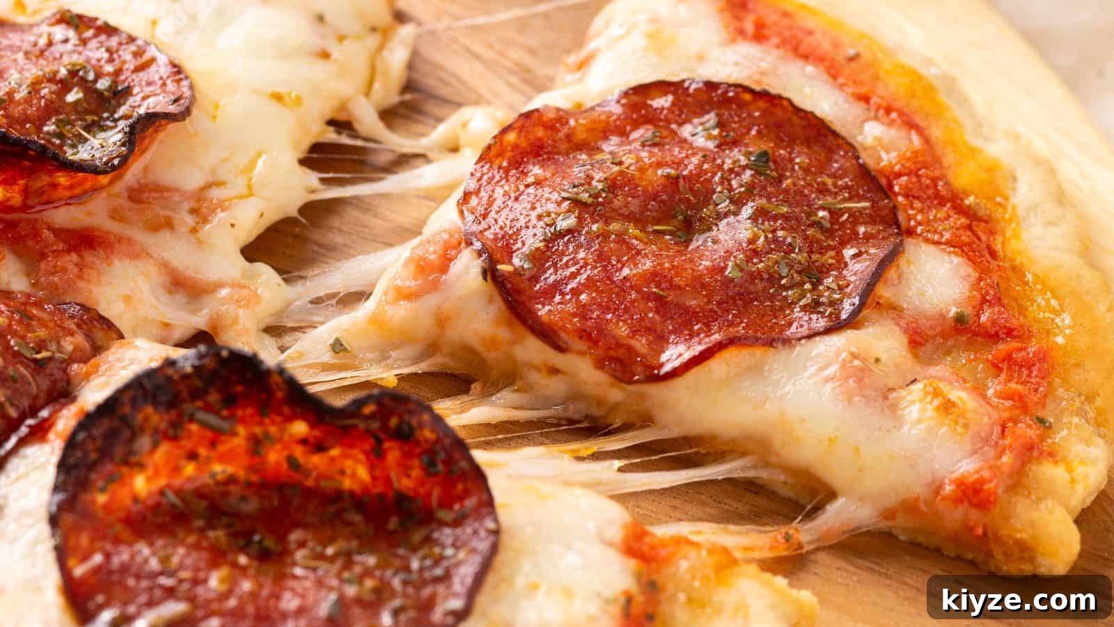 25 Comforting Main Dishes That Make You Forget the Grill 19 Close-up of a pepperoni pizza slice being lifted, showing melted cheese and tomato sauce.