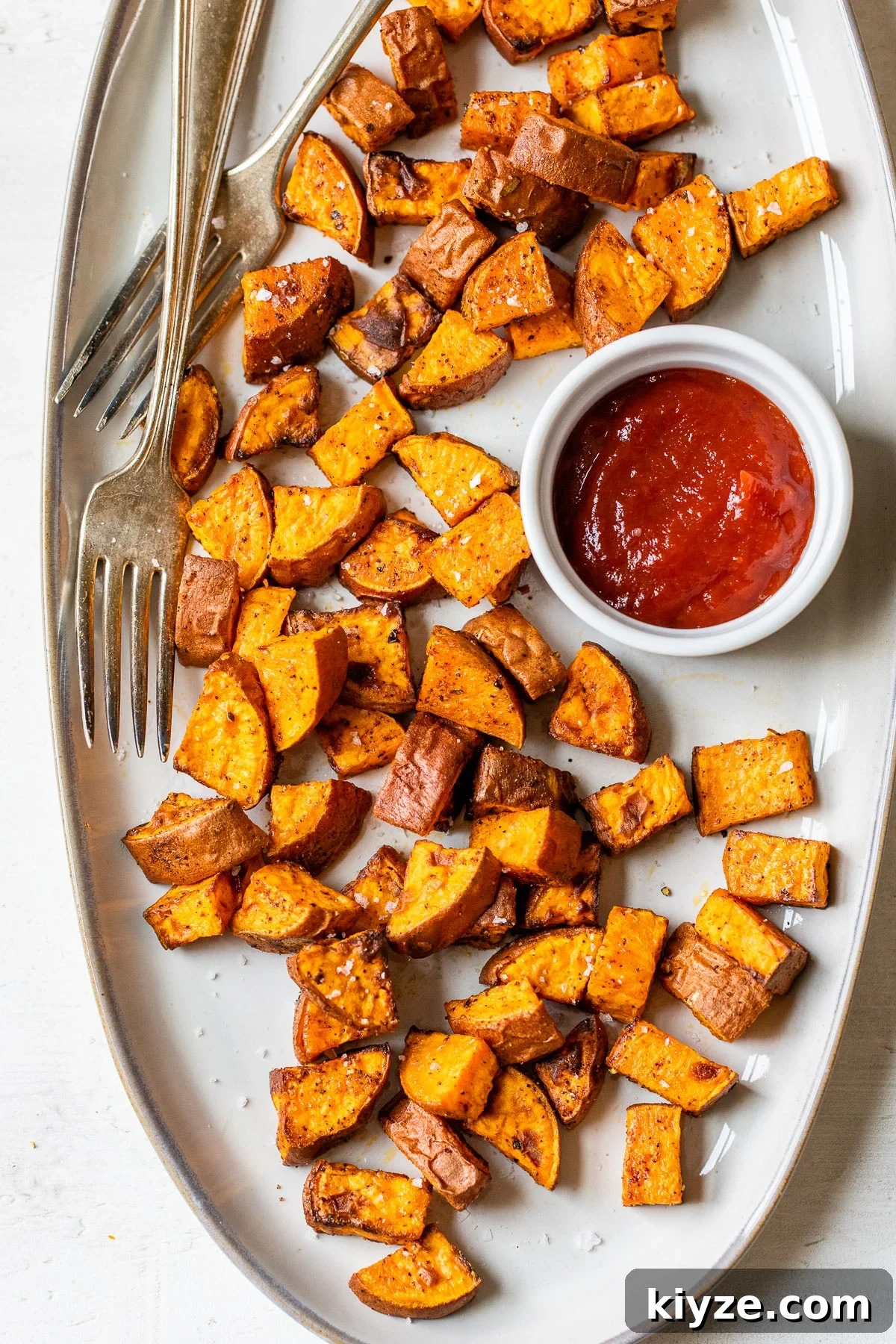 Crispy Air Fryer Sweet Potatoes: Quick Roasted Sweet Potato Recipe 5 cooked sweet potatoes on a plate with a side of ketchup