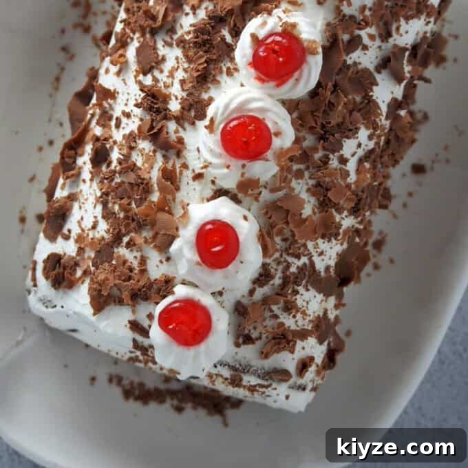 Black Forest Roll Cake Recipe – Chocolate Cherry Swiss Roll 9 top view of a Black Forest Swiss Roll Cake on a white serving platter.