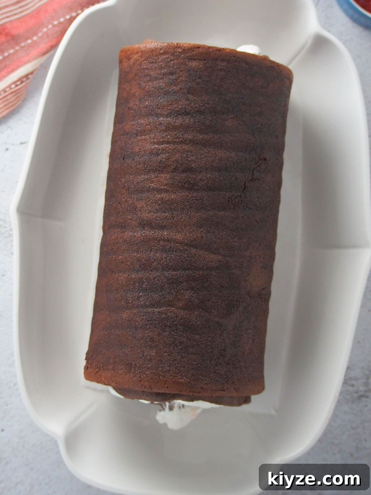 Black Forest Roll Cake Recipe – Chocolate Cherry Swiss Roll 7 rolled chocolate chiffon cake on a white platter.