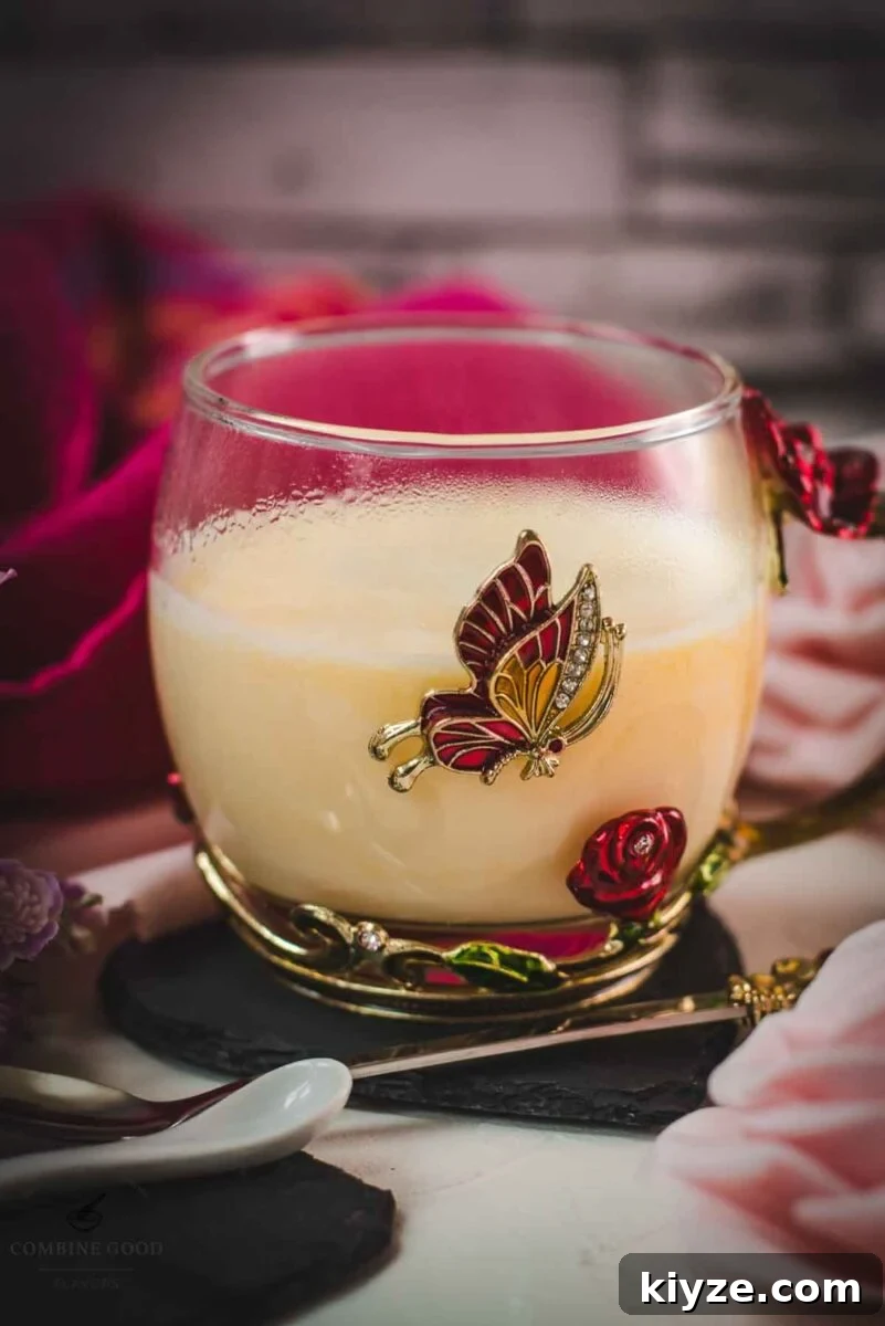 Classic Maraschino Milk Cocktail Recipe for Vintage Flavor 11 Creamy, dreamy Maraschino liqueur cocktail served in whimsical cup with red and golden butterflies and flowers. Placed on a black slate heart shaped coaster.