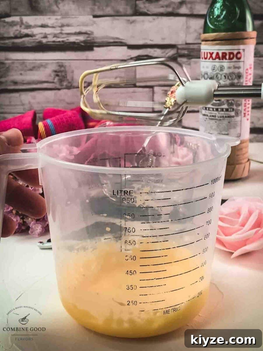 Classic Maraschino Milk Cocktail Recipe for Vintage Flavor 5 Egg yolk powdered sugar mixture in a mixing bowl next to a hand mixer.