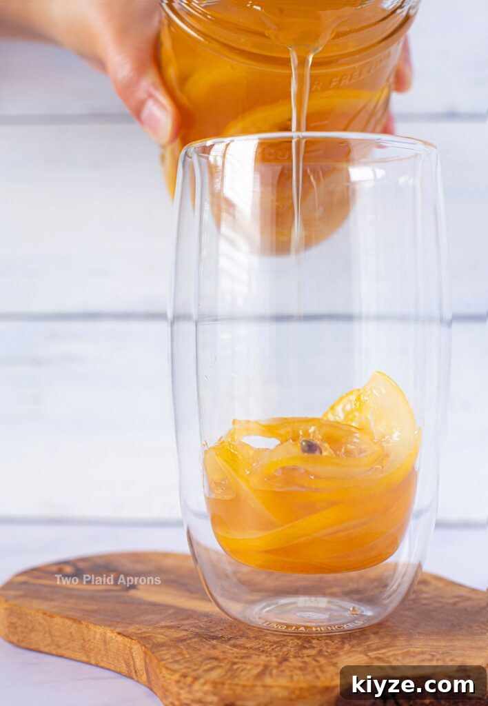 Pink Lemonade with Black Wolfberries: Refreshing Homemade Recipe 13 Pouring lemon syrup into a glass cup with candied lemon.