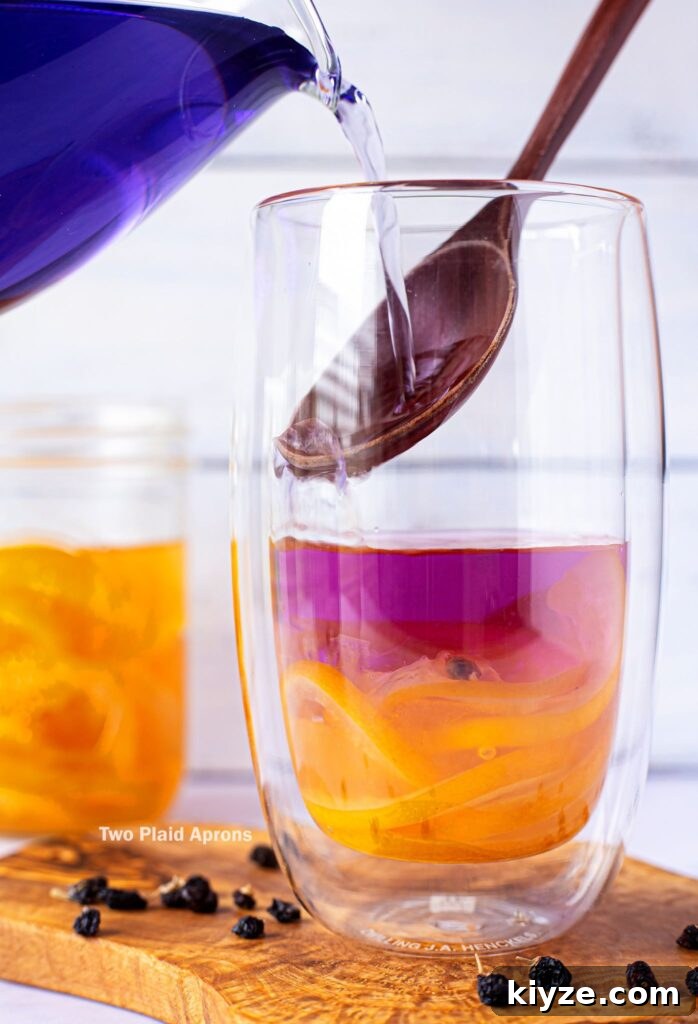 Pink Lemonade with Black Wolfberries: Refreshing Homemade Recipe 5 Gently pouring black wolfberry tea onto a spoon, into the cup with lemon syrup.