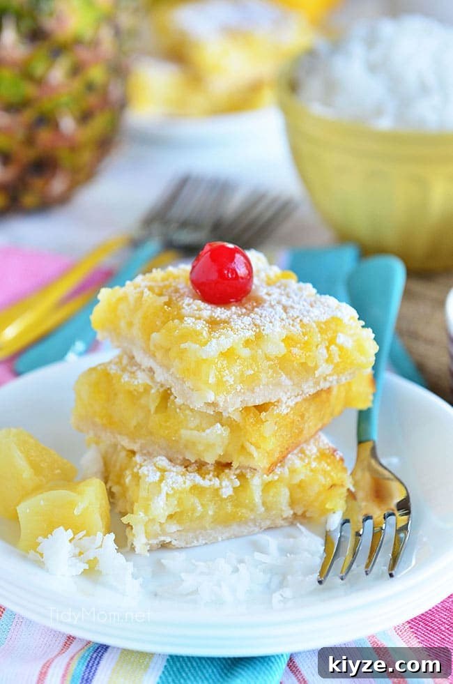 Pineapple Coconut Dessert Bars (Piña Colada) + Video 2 dessert bars on a white plate with a blue fork