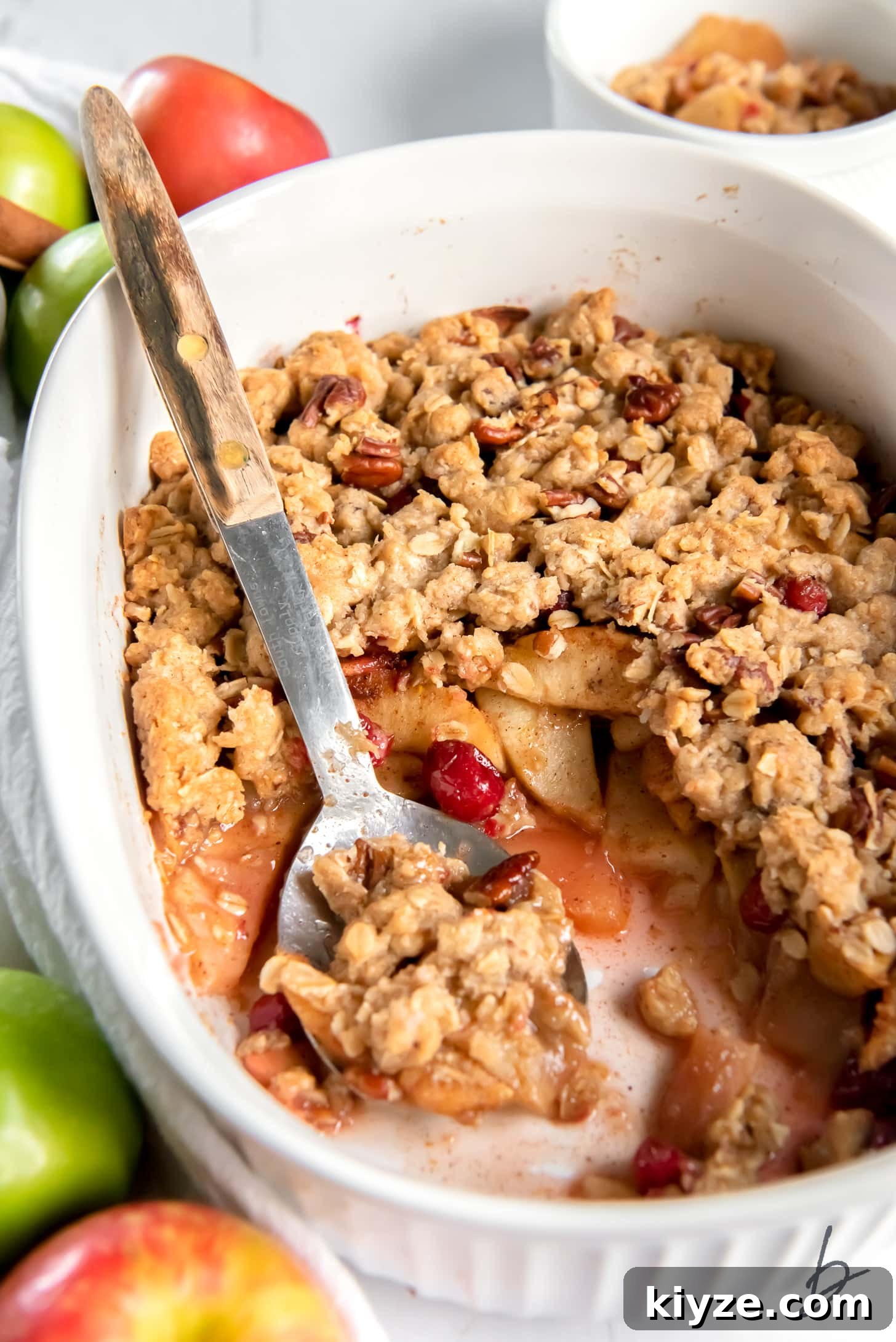 Apple Cranberry Crisp Recipe with Cinnamon Streusel 8 serving spoon holding scoop of apple cranberry crisp in a serving dish.