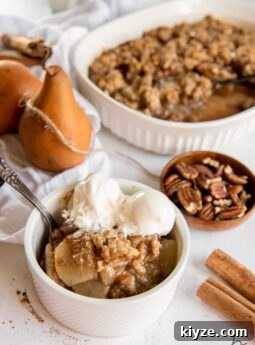 pear crisp in a bowl with vanilla ice cream next with pears and baking dish.