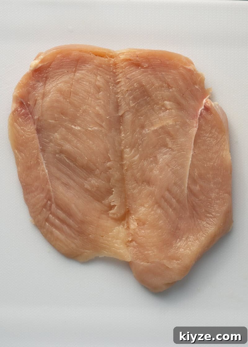 a butterflied chicken breast on a white cutting board