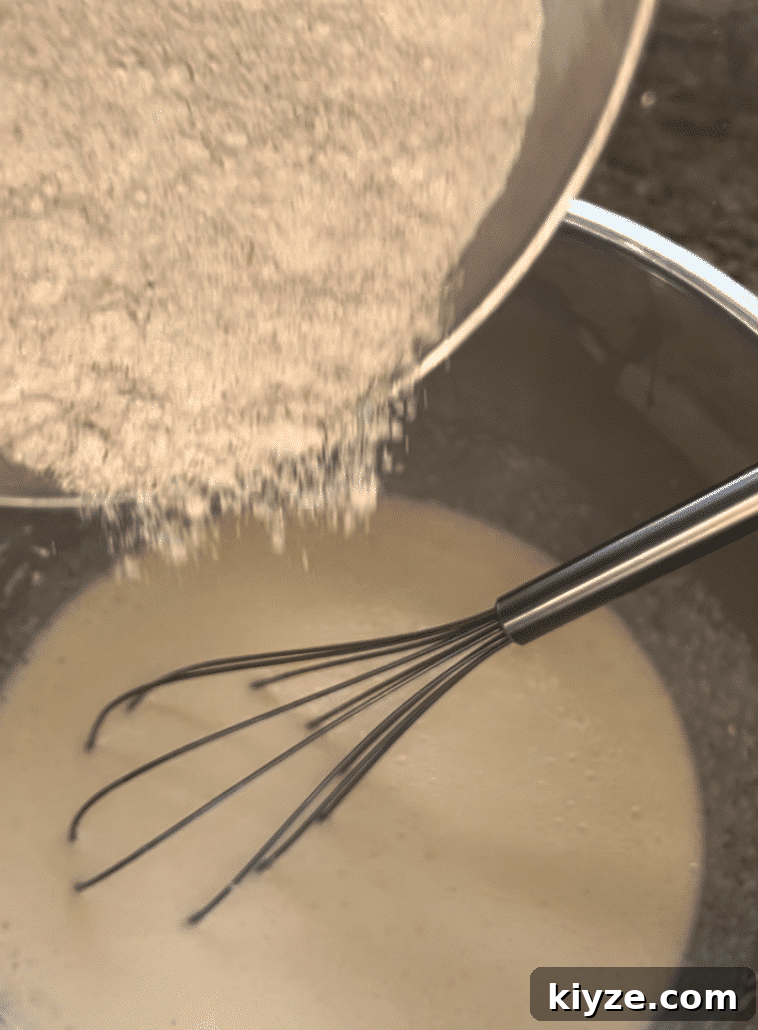 Sourdough Gingerbread Waffles Recipe — Crisp Spiced Morning Treat 5 Flour being added to a bowl of liquid ingredients with a whisk in the bowl.