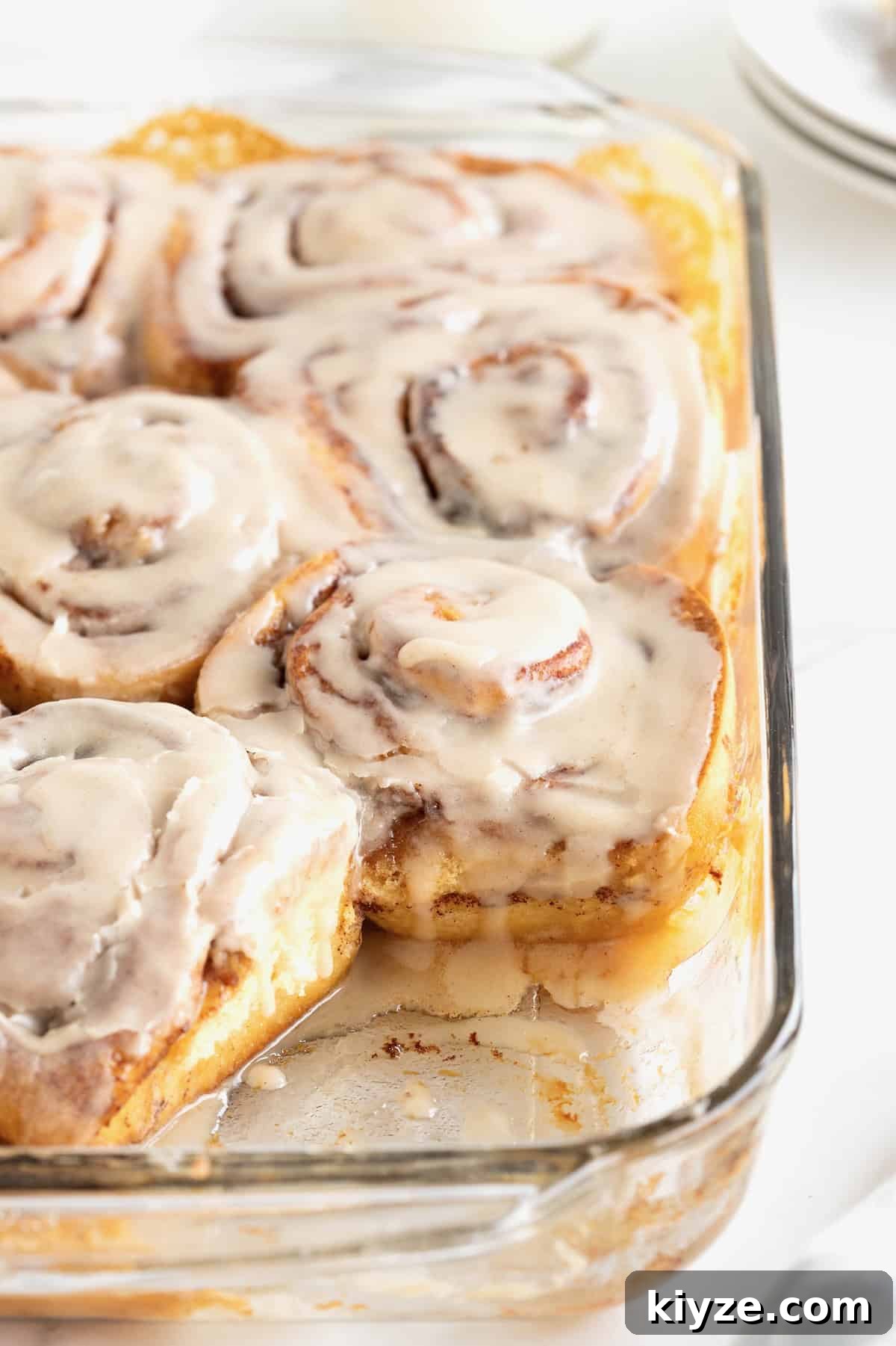 Quick Canned Cinnamon Rolls: Fast Oven & Air Fryer Hack 2 Store bought cinnamon rolls in a glass baking dish topped with icing.