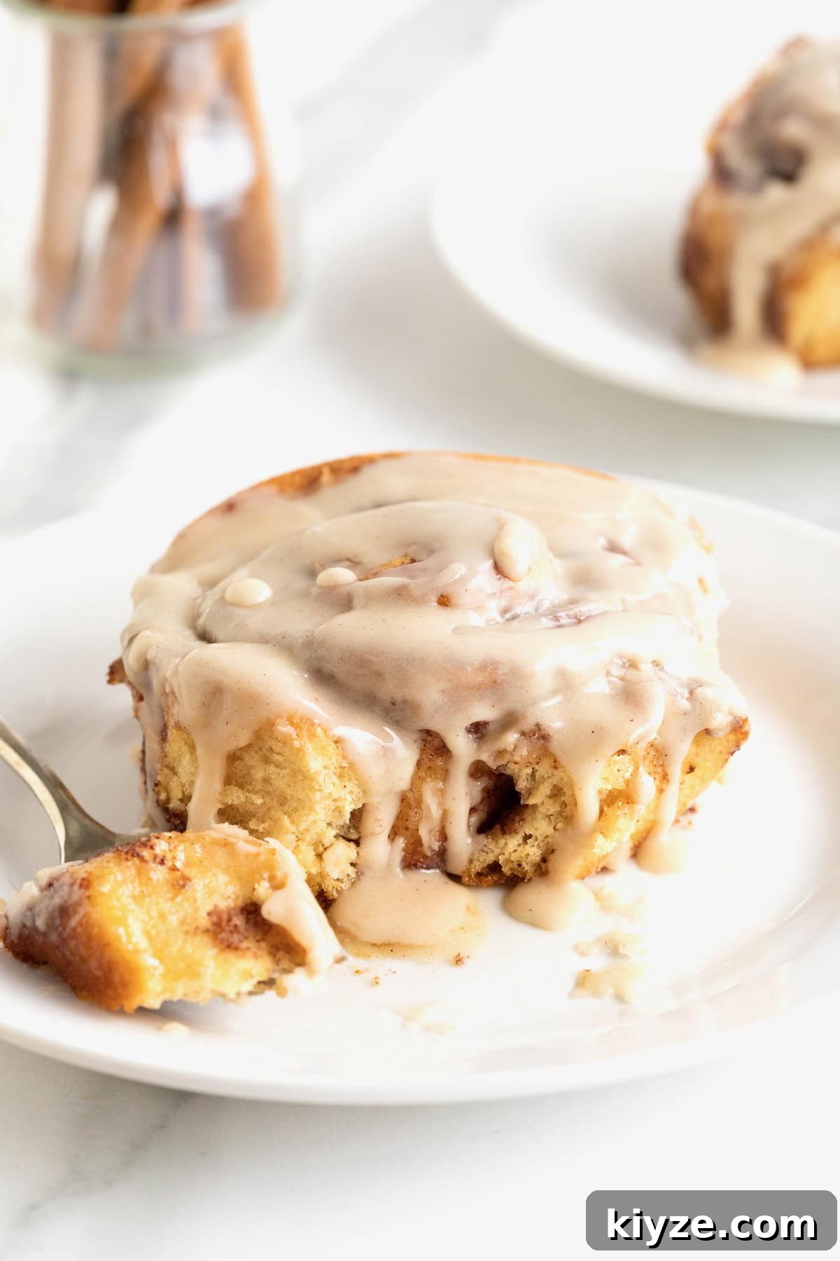Quick Canned Cinnamon Rolls: Fast Oven & Air Fryer Hack 3 A cinnamon roll covered in icing on a small white plate with a fork.
