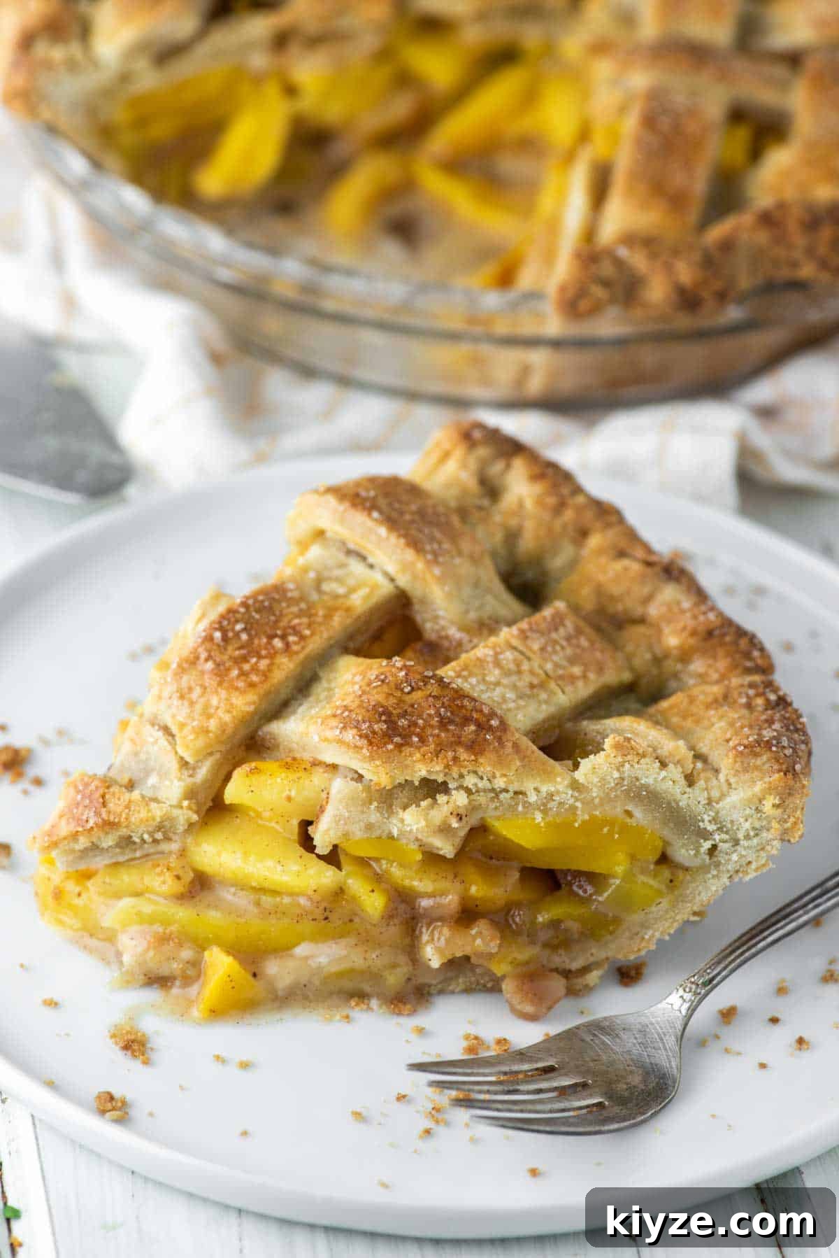 Peach and Mango Pie Recipe: Flaky Crust with Luscious Filling 7 slice of peach mango pie on white plate with fork