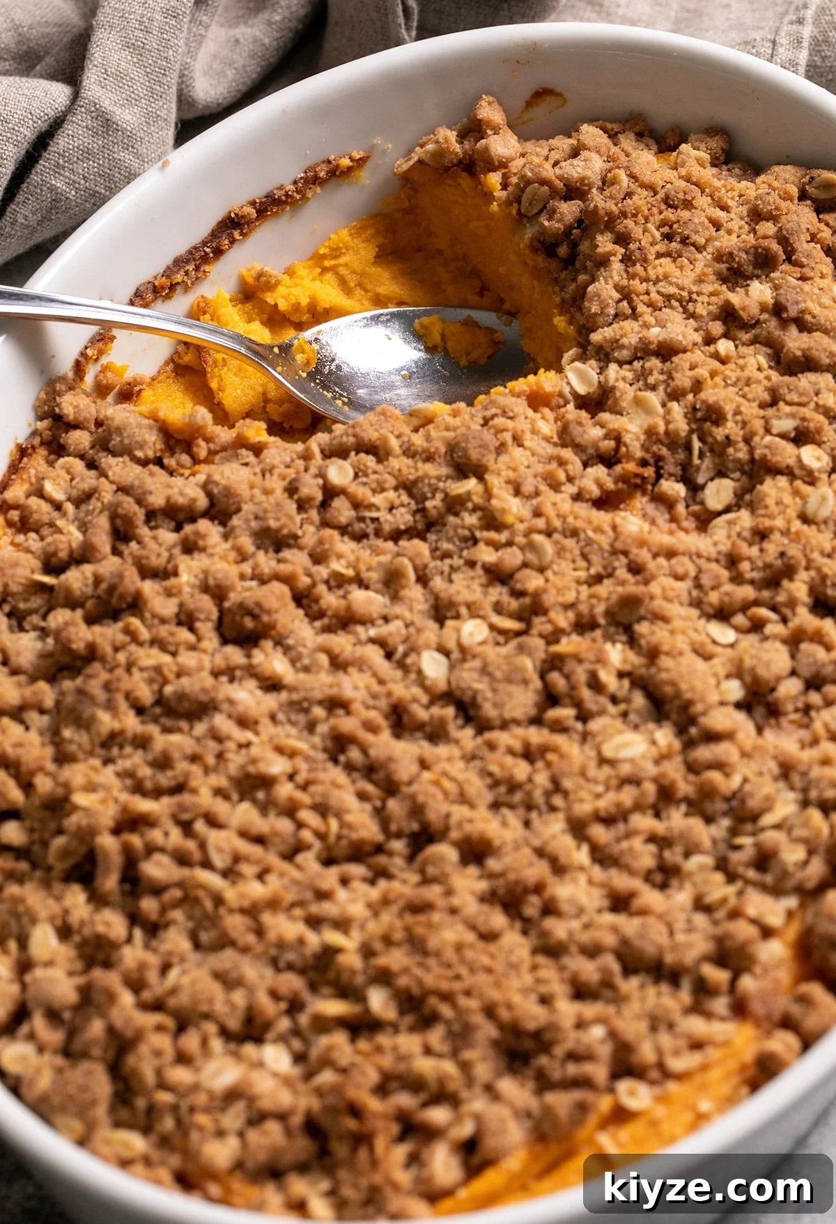 Gluten-Free Sweet Potato Casserole Recipe for Holidays 20 Sweet potato casserole in white baking dish with spoonful missing
