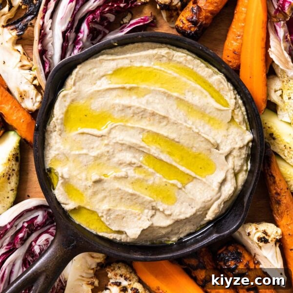 Authentic Baba Ganoush Recipe: Smoky Eggplant Dip Guide 6 Top down view of black cast iron skillet filled with Baba ganoush drizzled on top with olive oil sitting on wood board filled with grilled vegetables