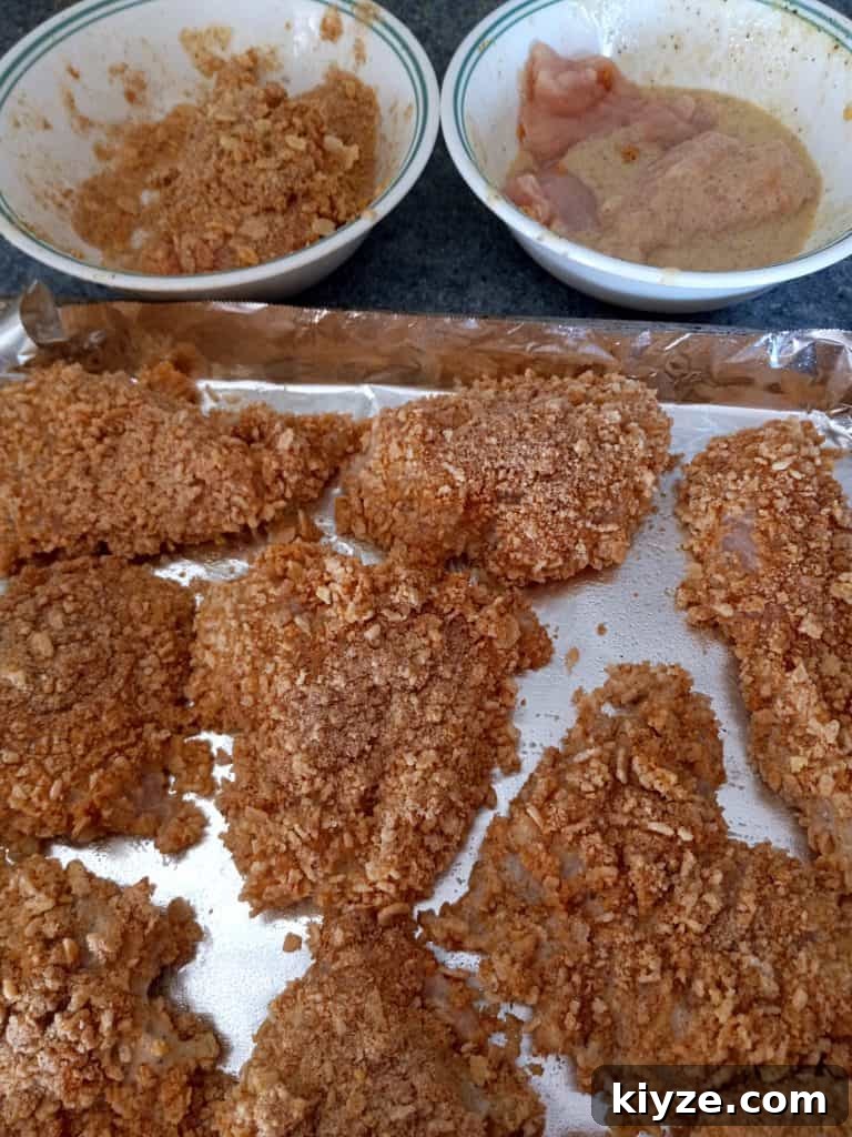 dipping chicken breast into Rice Krispies and placing them onto a large baking sheet.