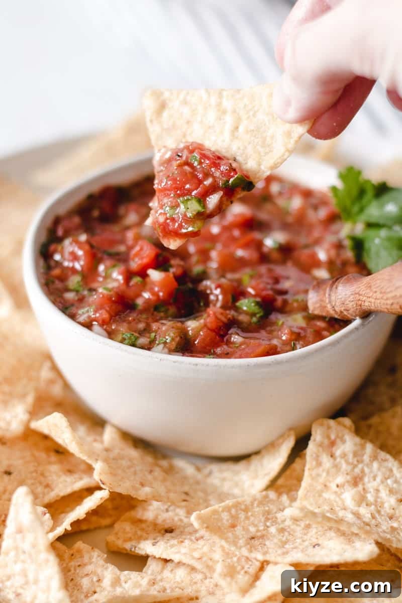 Dipping a tortilla chip into a bowl of salsa.