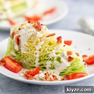 Classic Blue Cheese Wedge Salad with Crispy Bacon and Dressing 12 A blue cheese wedge salad with tomatoes and bacon on a white plate.