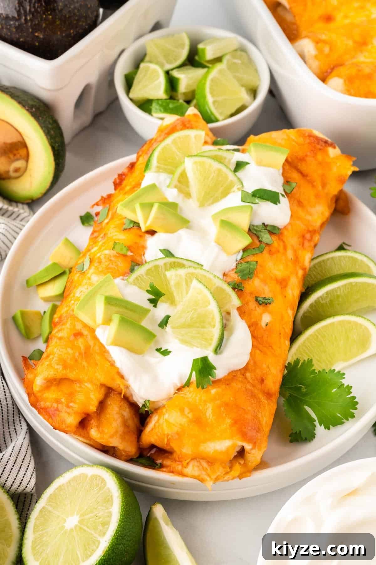 Sweet Potato and Black Bean Enchiladas with Chipotle Sauce 15 two enchiladas on a plate topped with sour cream, avocado, and lime