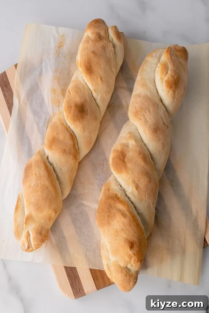 30-Minute Crusty Baguettes: Foolproof Recipe for Homemade Bread 11 two baked foolproof baguettes on a parchment paper covered wooden cutting board