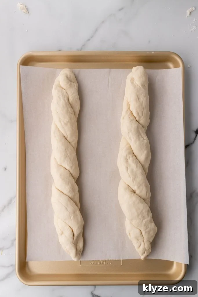 30-Minute Crusty Baguettes: Foolproof Recipe for Homemade Bread 10 two twisted unbaked loaves of french baguettes on a parchment paper covered baking pan