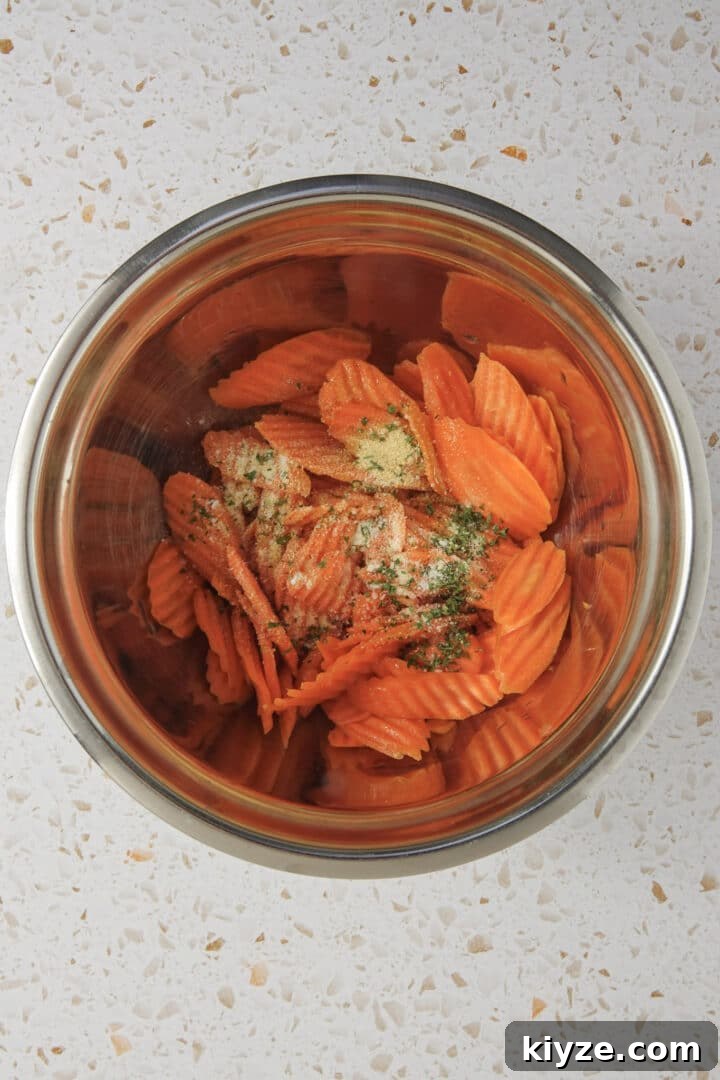 Crispy Air Fryer Carrot Chips Recipe 5 oil and spices added to carrot chips in a metal bowl