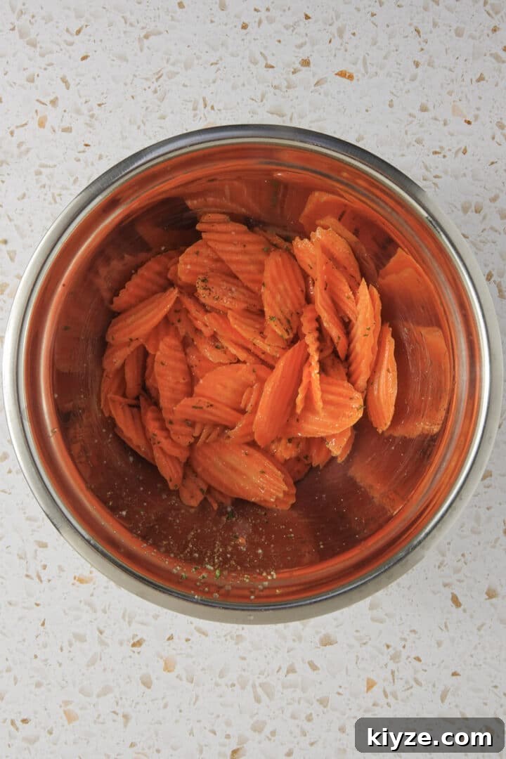 Crispy Air Fryer Carrot Chips Recipe 6 carrot chips tossed with oil and seasonings in a metal bowl