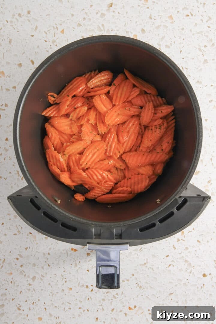 Crispy Air Fryer Carrot Chips Recipe 7 seasoned carrot chips in air fryer basket on kitchen counter