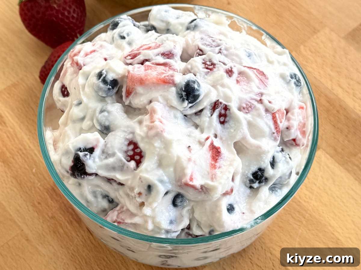 Whipped cottage cheese mixed with blueberries, strawberries, and blackberries in a glass bowl.