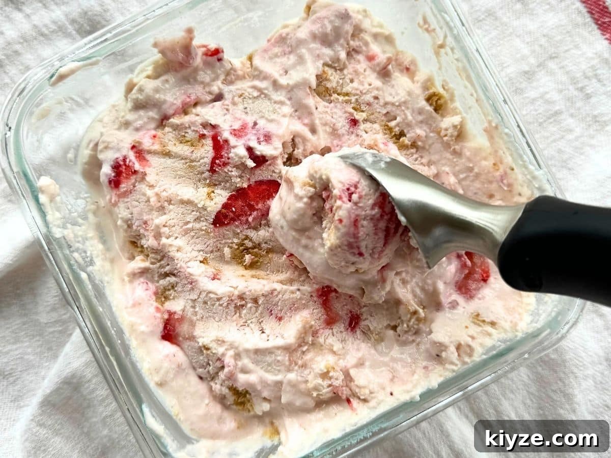Strawberry cottage cheese ice cream being scooped out of a square glass bowl.