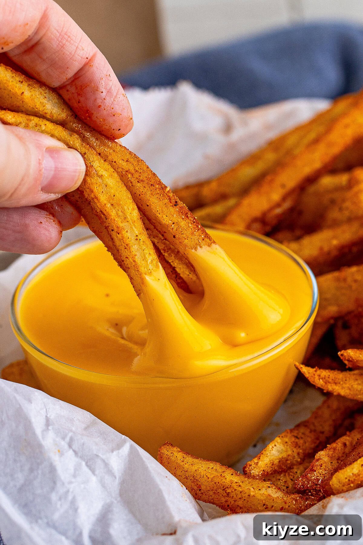 Dipping a fry into creamy copycat Taco Bell nacho cheese.