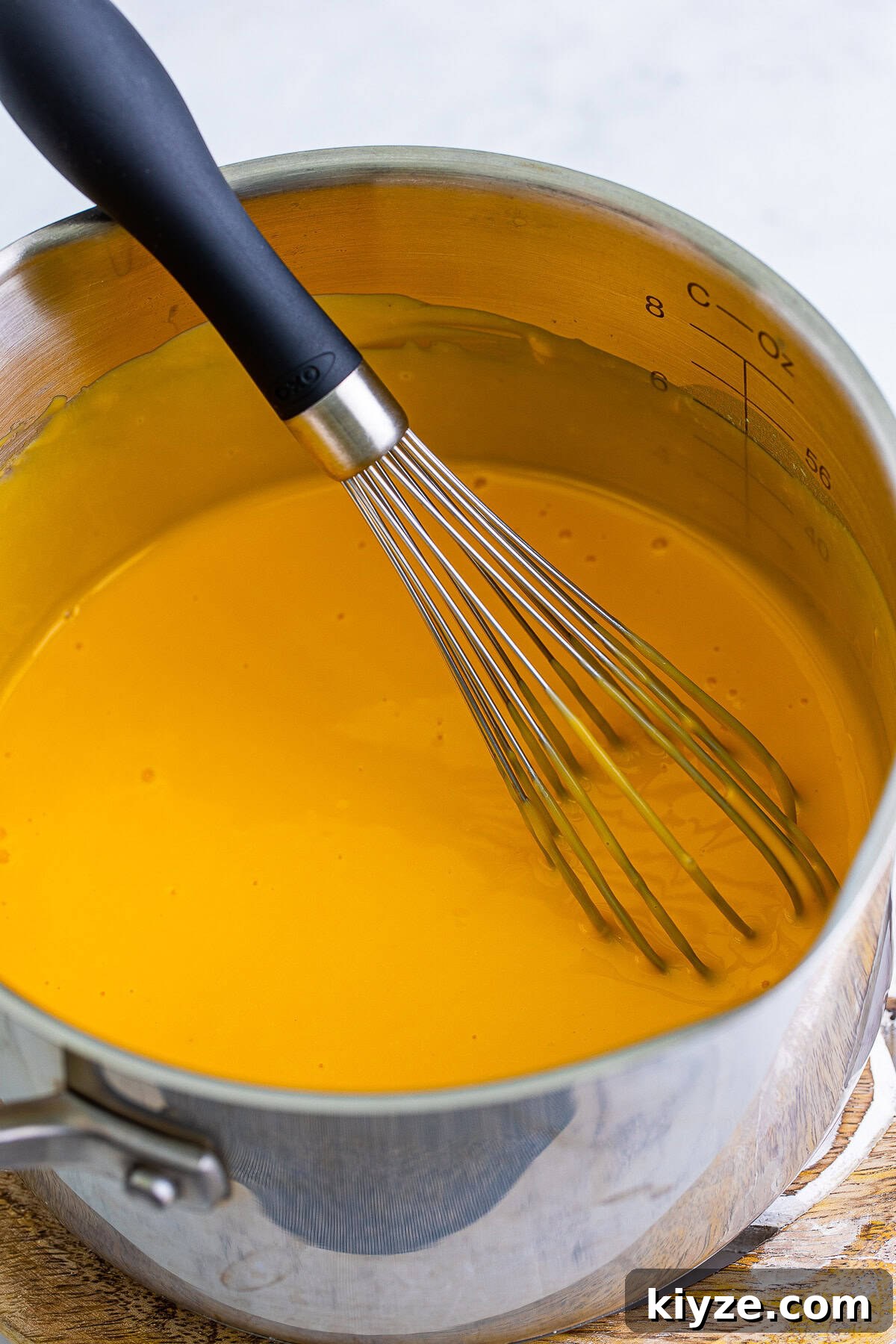 Whisking smooth melted copycat Taco Bell nacho cheese in a saucepan.