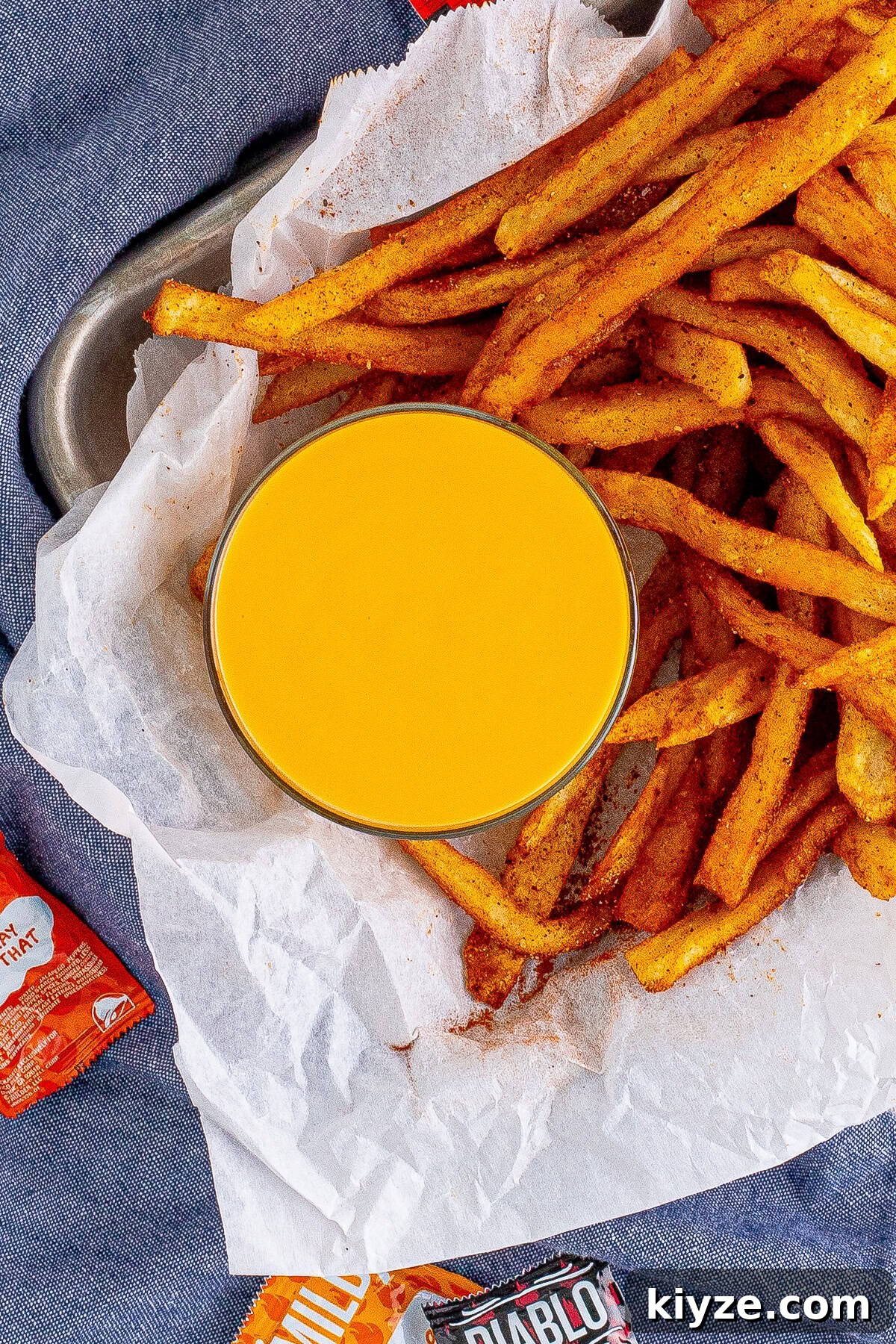 Bowl of copycat Taco Bell nacho cheese with a basket of fries.