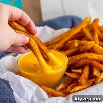 Nacho Fries Recipe being dipped into nacho sauce.