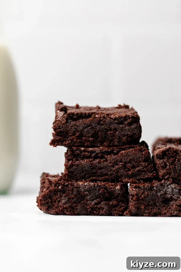 One-Bowl Fudgy Gluten-Free Brownies Recipe 14 sliced brownies (gluten free) on a parchment paper lined wood cutting board