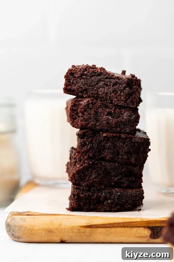 One-Bowl Fudgy Gluten-Free Brownies Recipe 4 Thick and chewy brownies stacked on a wood cutting board lined with white parchment paper