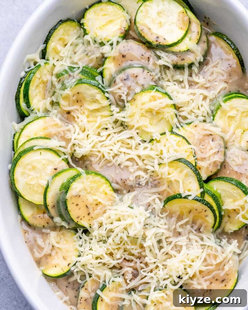 cheese added over the sliced zucchini before baking in a white dish 
