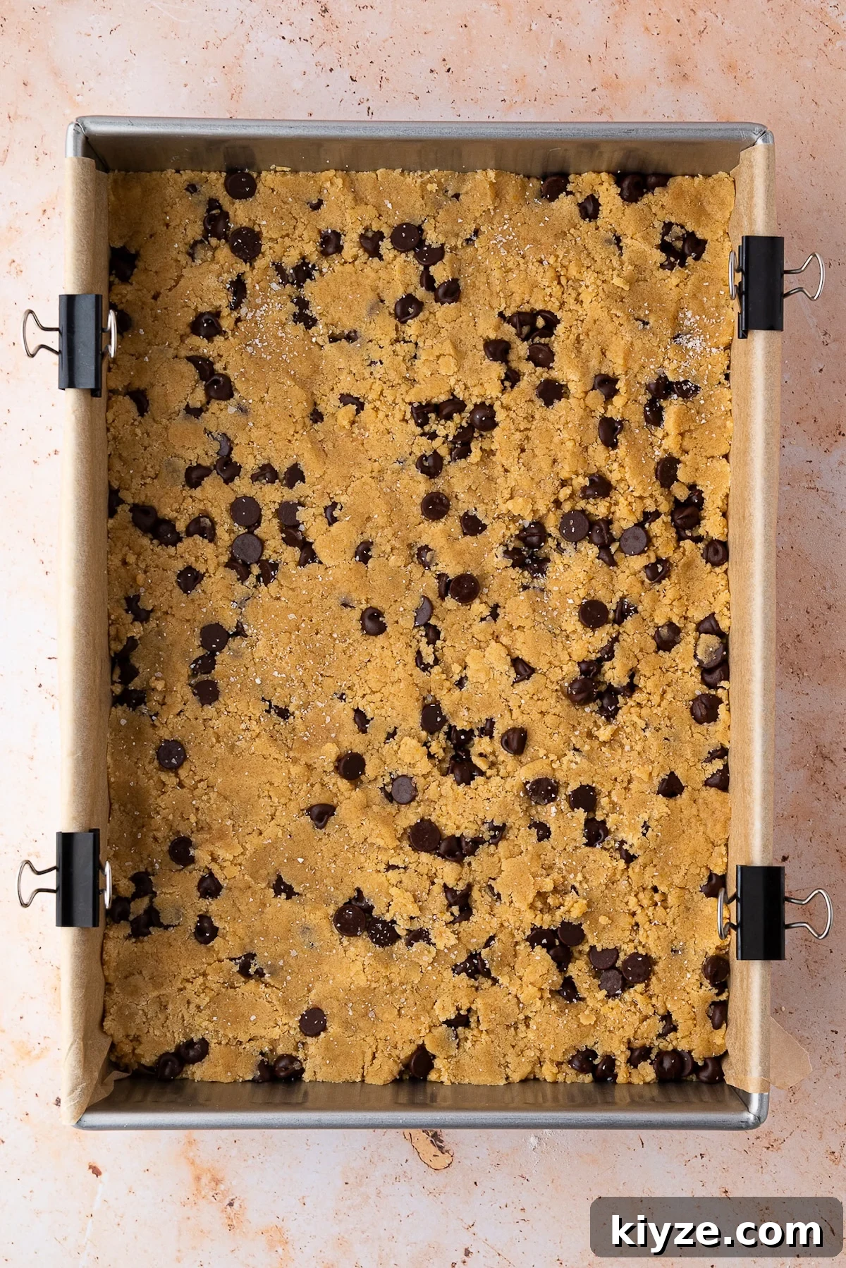 Bourbon Chocolate Chip Cookie Bars Recipe — Rich Boozy Dessert 8 9x13-inch pan of cookie bar dough gently pressed down before it bakes in the oven.