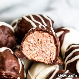 White Chocolate Raspberry Truffles Recipe: Rich Homemade Treats 3 Straight on shot of raspberry truffle cut in half on a pile of several.