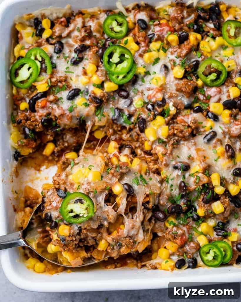Cheesy Taco Casserole: One-Pan Mexican Dinner Recipe 3 Cutting a serving of a Mexican casserole.