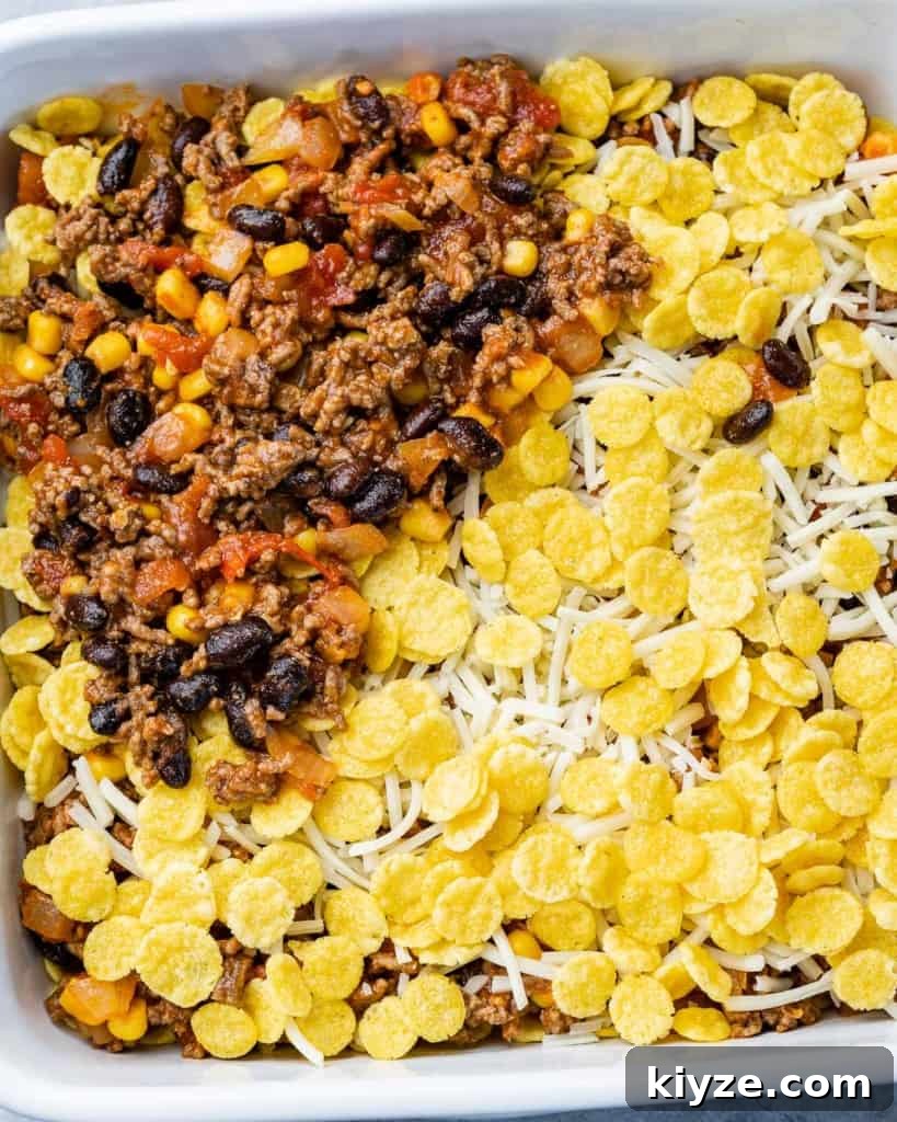 Cheesy Taco Casserole: One-Pan Mexican Dinner Recipe 6 Layering beef mixture, cornflakes and cheese in a baking dish.