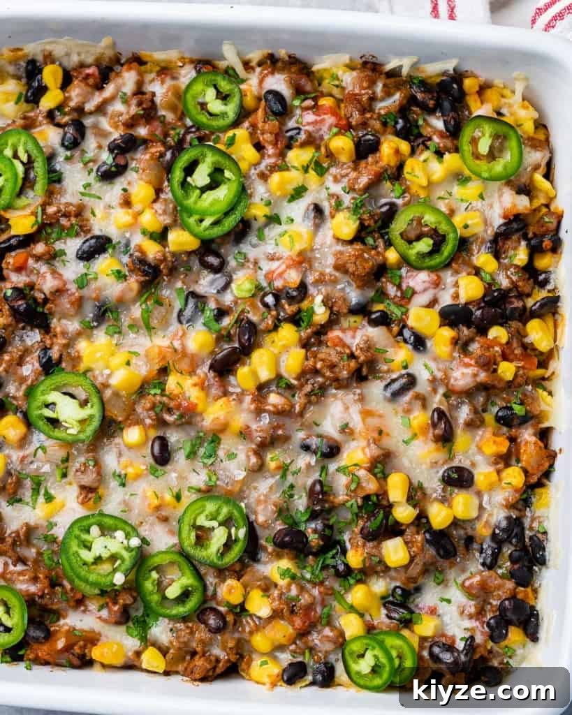 Cheesy Taco Casserole: One-Pan Mexican Dinner Recipe 8 top view taco casserole in a white dish, topped with sliced jalapenos