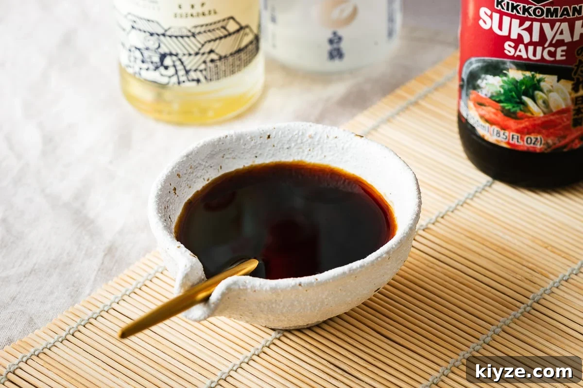 Sukiyaki sauce in a sauce bowl with a bottle of Kikkoman sukiyaki sauce in the background.