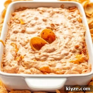 Creamy Cheesy Refried Bean Dip for Parties and Game Day 14 Refried bean dip with chips sticking out.