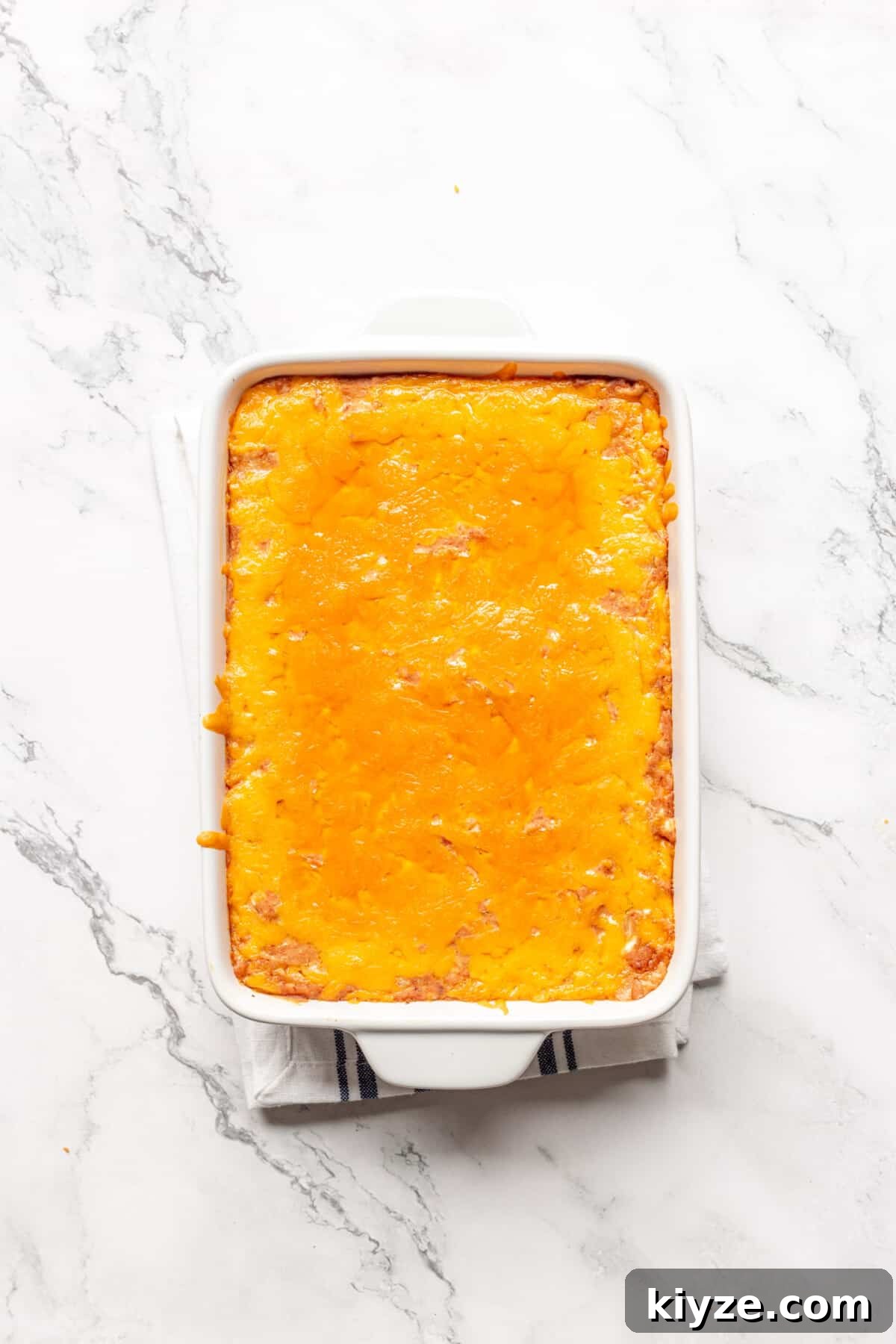 Creamy Cheesy Refried Bean Dip for Parties and Game Day 8 Cheesy refried bean dip in baking dish.